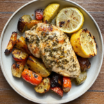 A beautifully plated AIP lemon herb chicken with roasted zucchini, Brussels sprouts, and carrots, garnished with fresh rosemary.