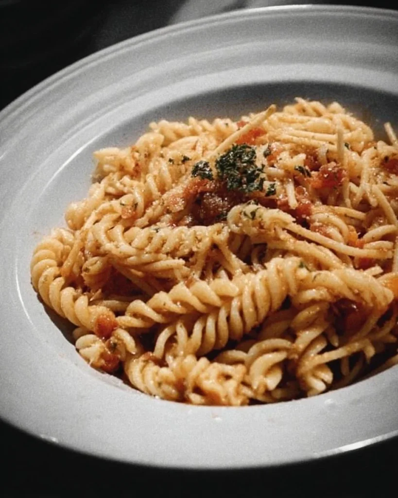 A plate of Midnight Pasta garnished with fresh herbs and cheese
